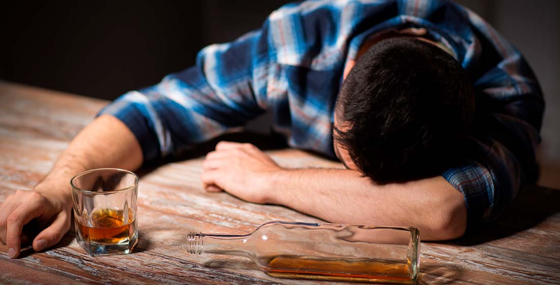 мужчина спит за столом с алкоголем