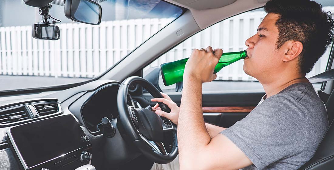 мужчина пьет алкоголь за рулем автомобиля